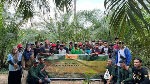 Indonesische mannen en vrouwen poseren naast een spandoek, met op de achtergrond palmen.