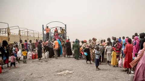 Mensen bij de Zuid-Sudanese grens op weg naar ons ons vluchtelingenkamp in Renk. Ze staan in de rij voor de vrachtwagen.
