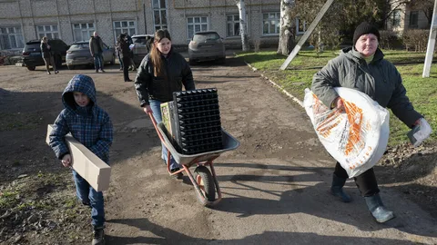 Drie mensen dragen landbouwproducten.