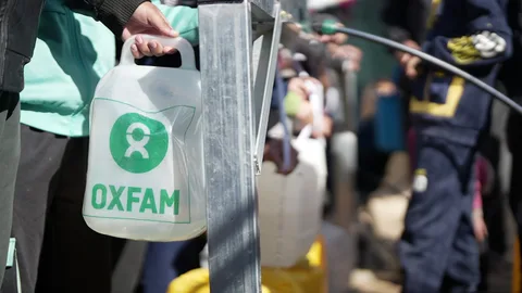 Mensen vullen een watertank met het Oxfam-logo erop.