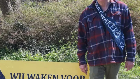 Joop staat naast een bord met de tekst: Wij waken voor het klimaat.