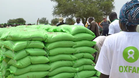 Hulpverleners van Oxfam Novib delen zakken met eten uit aan vluchtelingen