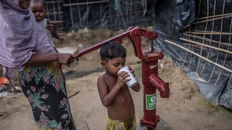 Sofia en haar zoontje halen water bij een nieuwe waterpomp.