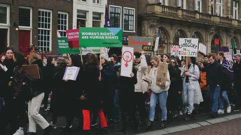 Foto van de vrouwenmars in Amsterdam. De demonstranten hebben borden met daarop teksten zoals "Women's rights are human rights".