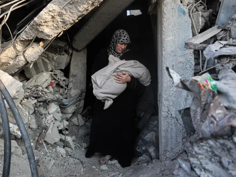 Palestijnse vrouw draagt overleden kind uit een verwoest gebouw.