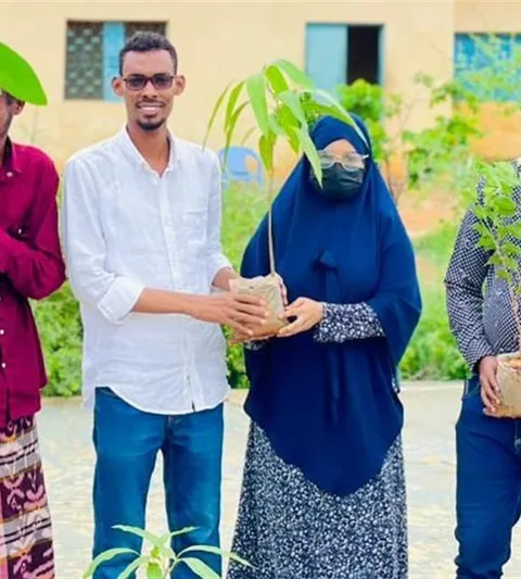 Photograph of a group of people holding young trees ready to be planted