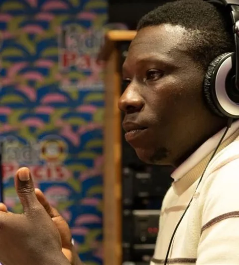 A man wearing headphones sits in front of a microphone.