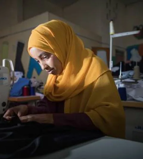 A young woman with a sewing machine producing uniforms