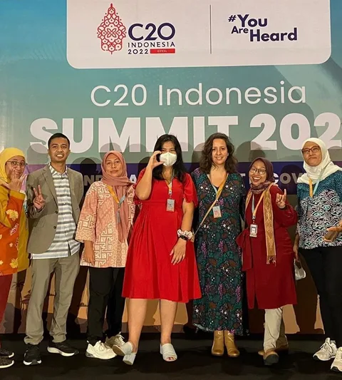 People from the Oxfam delegation stand in front of a banner of the C20 Bali summit.