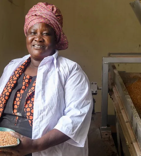 Florence Okot holding basket with grains