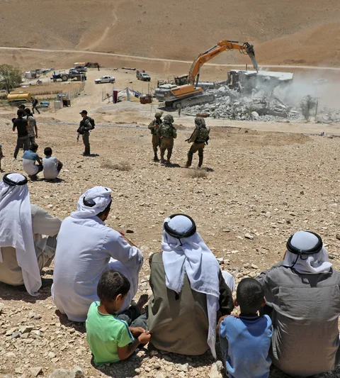 Bewoners kijken toe hoe Israëlische bulldozer een Palestijns huis sloopt