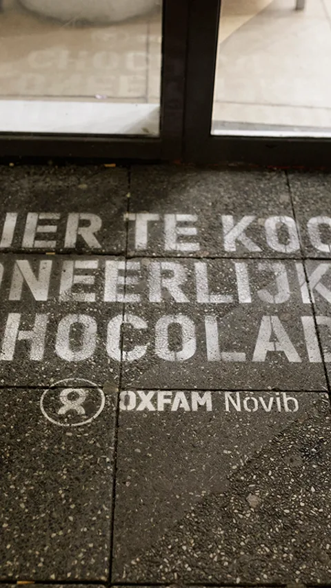 Green graffiti voor een supermarktdeur waarop 'Hier te koop oneerlijk chocolade'
