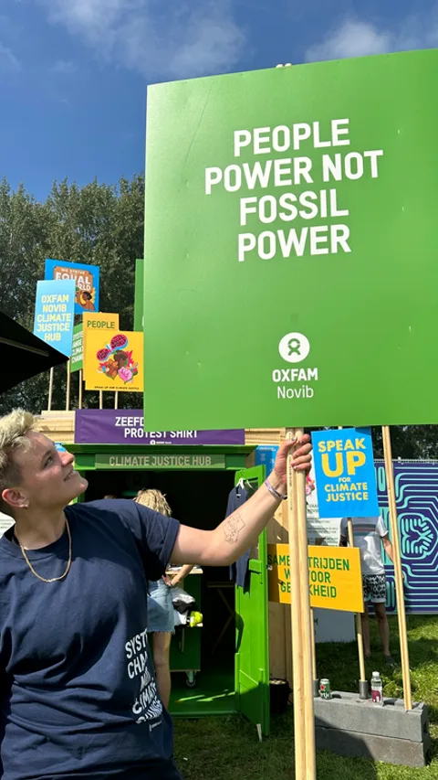 Een klimaatactivist houdt een groen protestbord vast met de tekst 'People power, not fossil power'