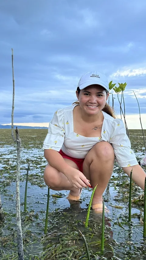 Activist Marinel hurkt naast jonge mangrovebomen die ze heeft geplant