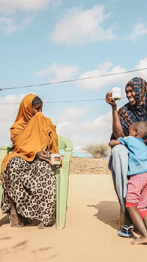 Vier Keniaanse vrouwen zitten naast elkaar iets te drinken.