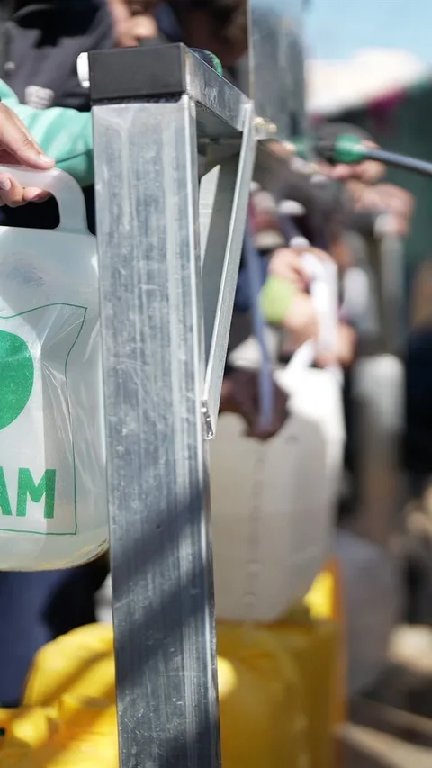 Mensen vullen een watertank met het Oxfam-logo erop.