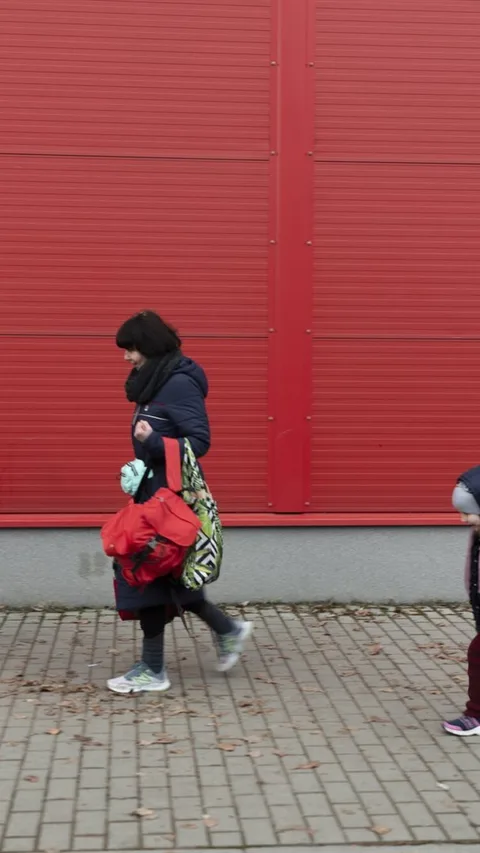 Migranten lopen met hun spullen langs een gebouw